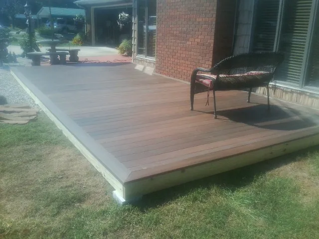New wood deck and wicker chair beside a brick house in Brunswick