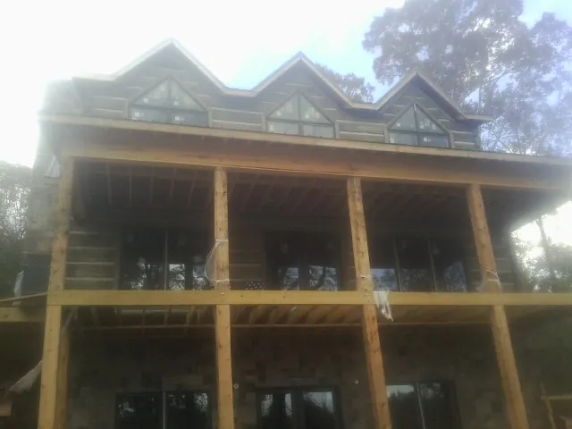 Dormers and porch framing on a large log home under construction — Roof Coating work by our crew in Brunswick