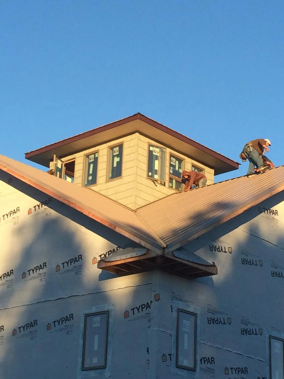 Roofers working around a rooftop cupola on a new metal roof at sunset — Roof Waterproofing in Brunswick by Roofing Brothers